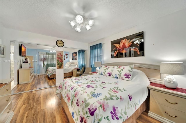 bedroom with ceiling fan, a textured ceiling, hardwood / wood-style flooring, and a closet