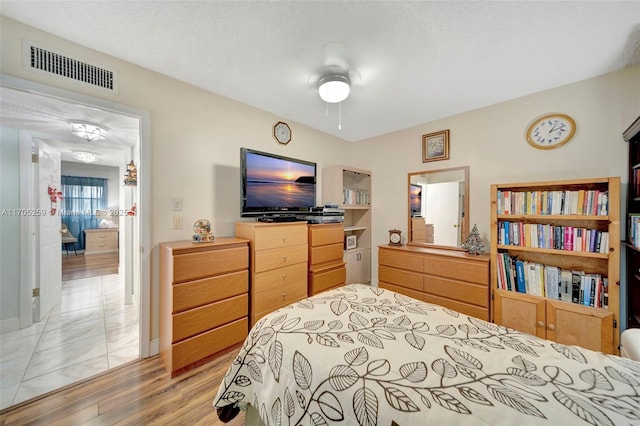 bedroom featuring ceiling fan, hardwood / wood-style floors, and a textured ceiling