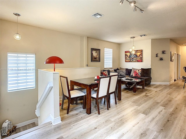 dining room featuring rail lighting and light hardwood / wood-style flooring