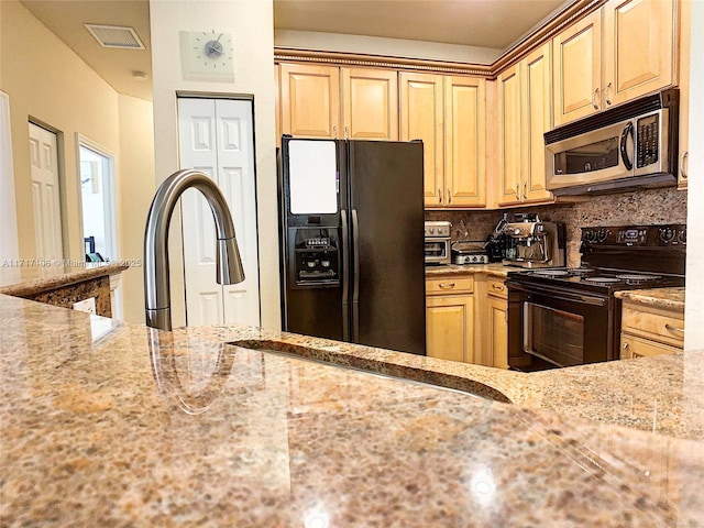 kitchen with decorative backsplash, light stone counters, and black appliances