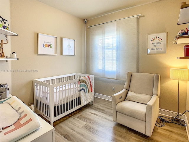 bedroom with hardwood / wood-style floors and a nursery area