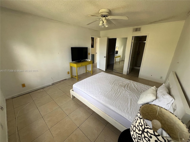 tiled bedroom with ceiling fan and a textured ceiling