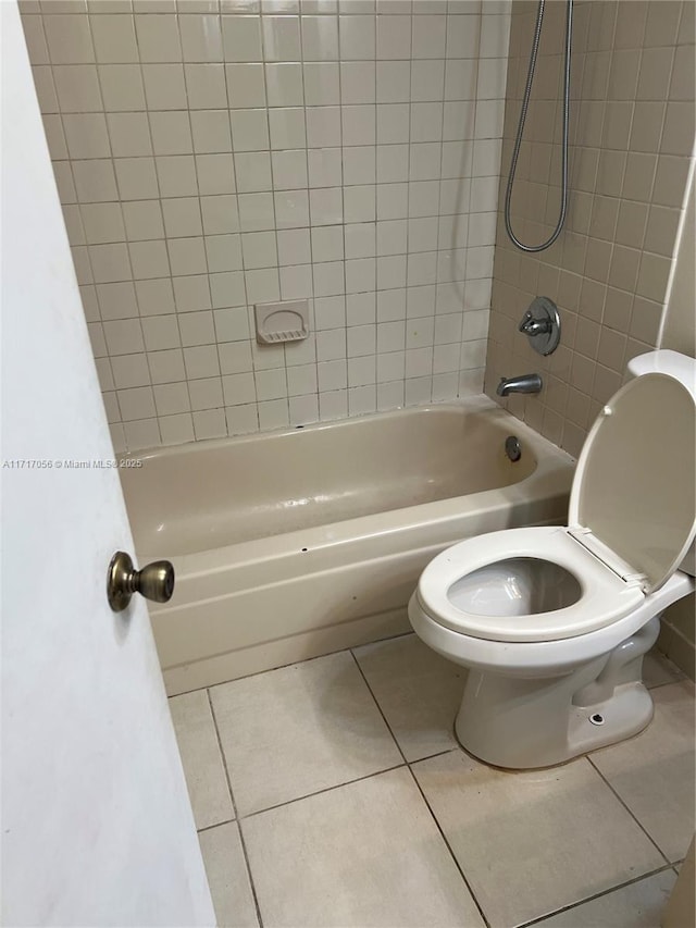 bathroom featuring tile patterned flooring, toilet, and tiled shower / bath