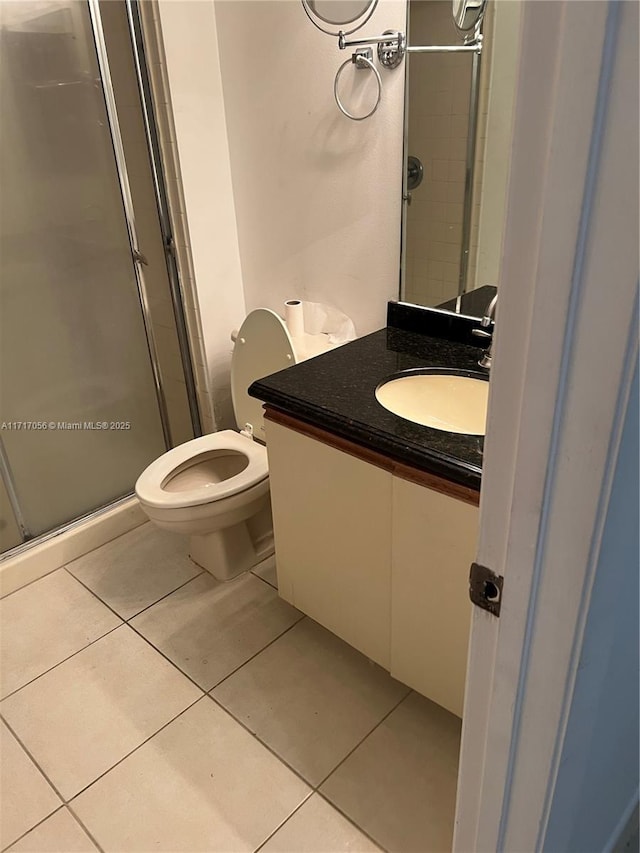 bathroom with tile patterned floors, vanity, toilet, and a shower with shower door