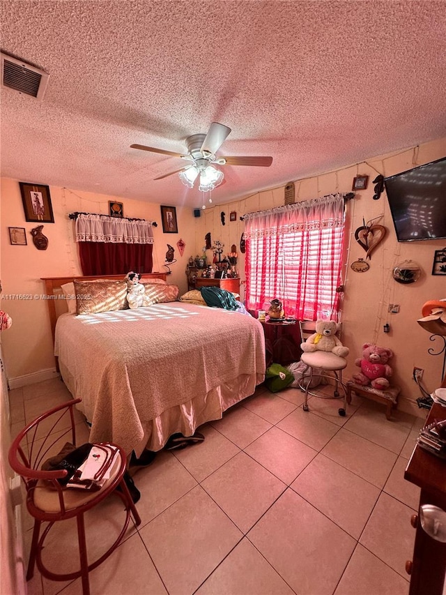 tiled bedroom with ceiling fan and a textured ceiling