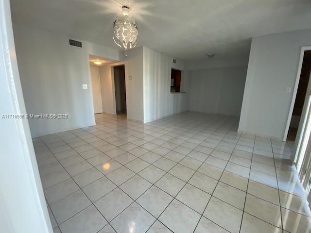 spare room featuring a notable chandelier and light tile patterned flooring