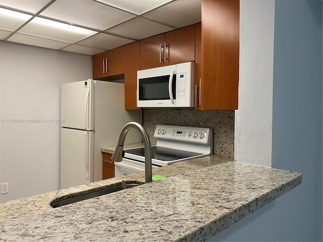 kitchen featuring a paneled ceiling, white appliances, and backsplash