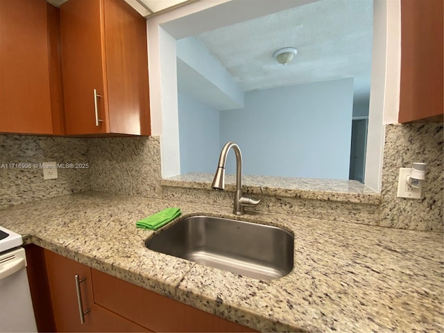 kitchen with backsplash, light stone countertops, and sink