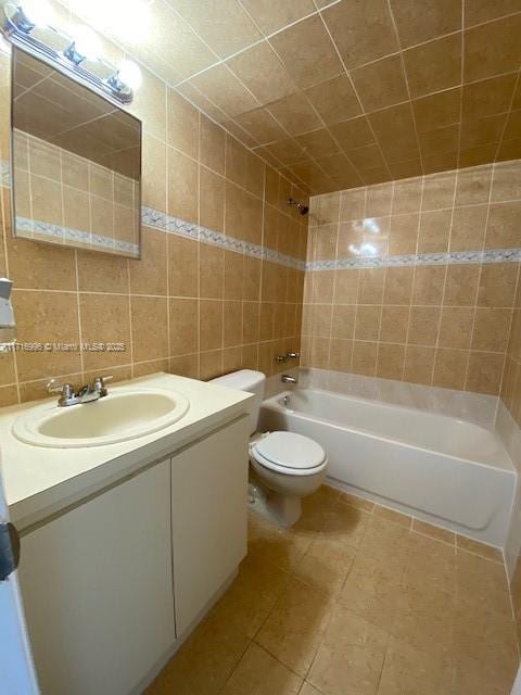 full bathroom featuring tile patterned flooring, bathtub / shower combination, toilet, vanity, and tile walls