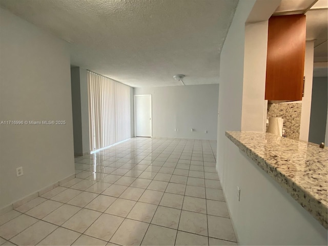 tiled empty room featuring a textured ceiling