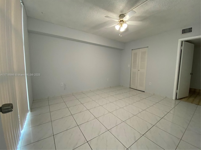 unfurnished bedroom featuring ceiling fan, light tile patterned floors, a textured ceiling, and a closet