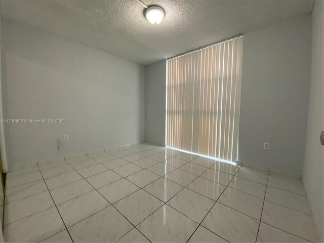 empty room featuring light tile patterned floors and a textured ceiling