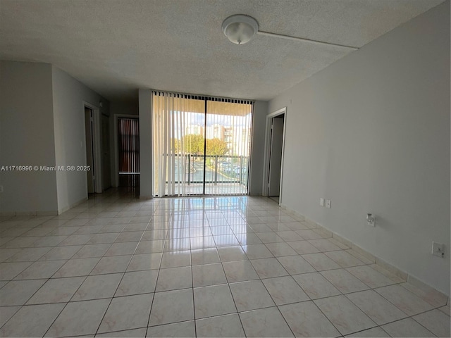 tiled spare room with a textured ceiling and a wall of windows