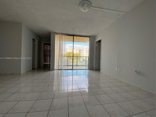 empty room with light tile patterned floors, a textured ceiling, and expansive windows