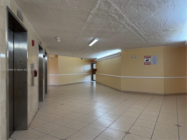 2055 SW 122nd Ave Unit 205, Miami, FL 33175 - corridor featuring light tile patterned floors, elevator, baseboards, and a textured ceiling