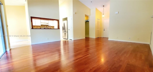 unfurnished room featuring hardwood / wood-style flooring and high vaulted ceiling