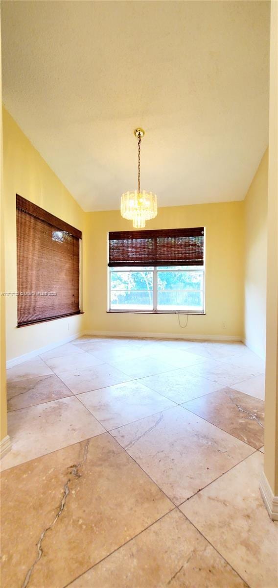 empty room with a healthy amount of sunlight, an inviting chandelier, and lofted ceiling