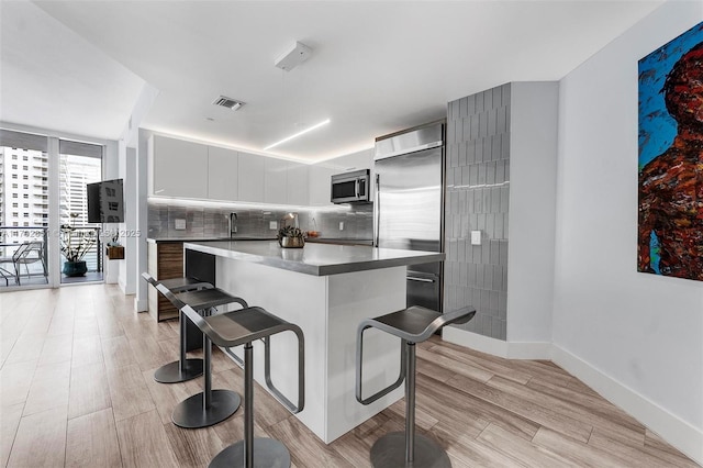 kitchen featuring decorative backsplash, appliances with stainless steel finishes, a breakfast bar, white cabinets, and a kitchen island