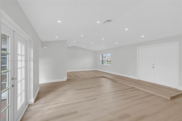 unfurnished room with lofted ceiling and light wood-type flooring