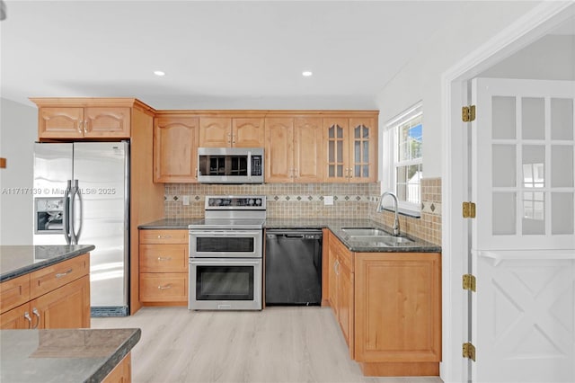 kitchen with tasteful backsplash, sink, appliances with stainless steel finishes, and light hardwood / wood-style flooring