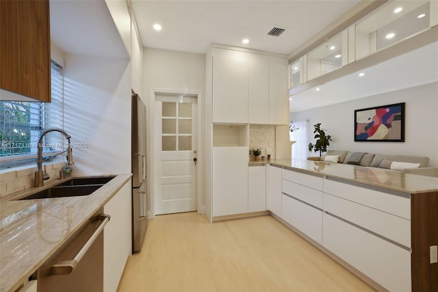 kitchen featuring light stone countertops, modern cabinets, decorative backsplash, and a sink