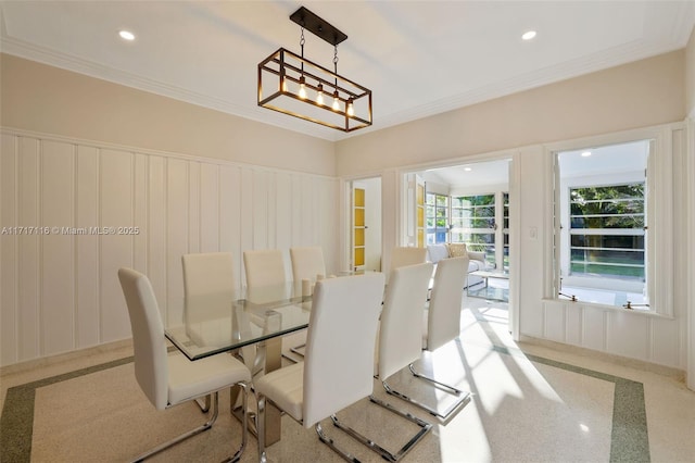 dining area with ornamental molding, a decorative wall, a chandelier, and wainscoting