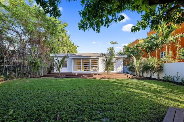 back of property with a lawn, a wooden deck, and a fenced backyard