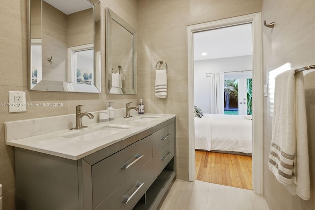 ensuite bathroom with connected bathroom, double vanity, and a sink