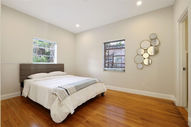 bedroom with recessed lighting, wood finished floors, and baseboards