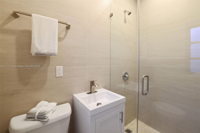 bathroom featuring vanity, toilet, a stall shower, and tile walls