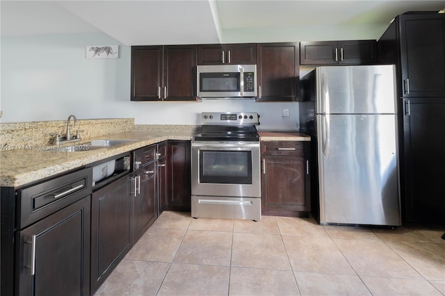 kitchen with appliances with stainless steel finishes, dark brown cabinetry, light tile patterned floors, and sink