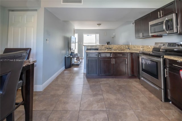 kitchen with light stone counters, sink, light tile patterned flooring, and appliances with stainless steel finishes