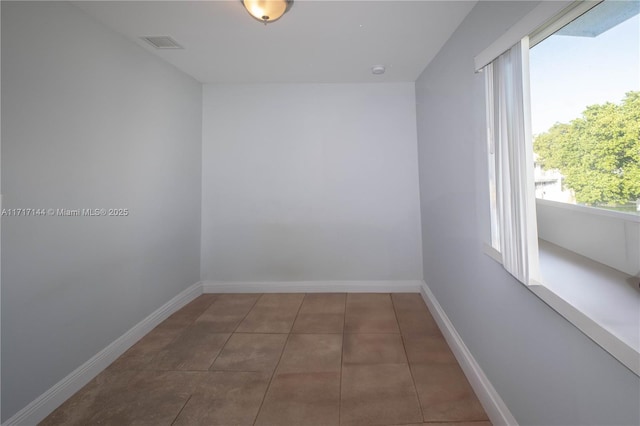 empty room featuring a wealth of natural light and dark tile patterned floors