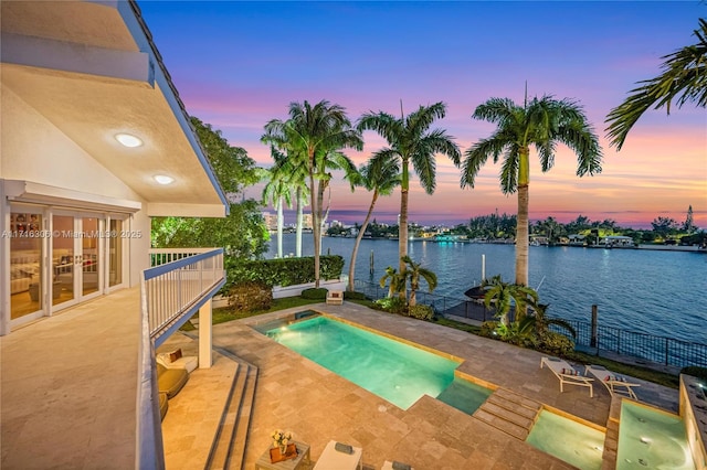 pool at dusk featuring a patio area and a water view