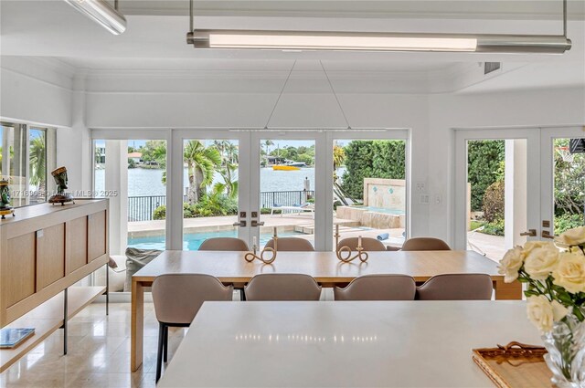 sunroom featuring french doors and a water view