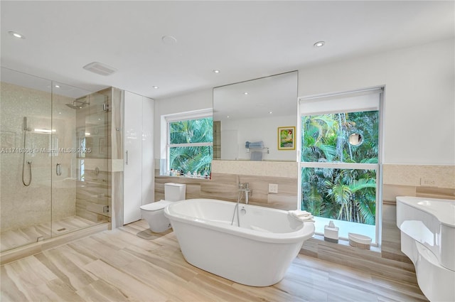 bathroom with shower with separate bathtub, toilet, and wood-type flooring