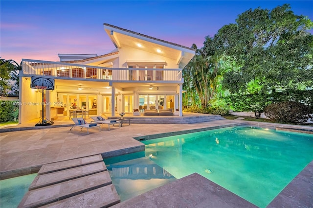 pool at dusk with french doors, an outdoor hangout area, ceiling fan, and a patio area