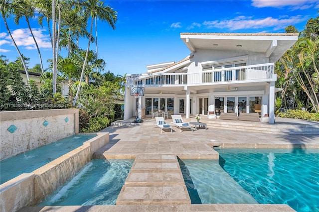 rear view of house featuring ceiling fan, french doors, pool water feature, a balcony, and a patio