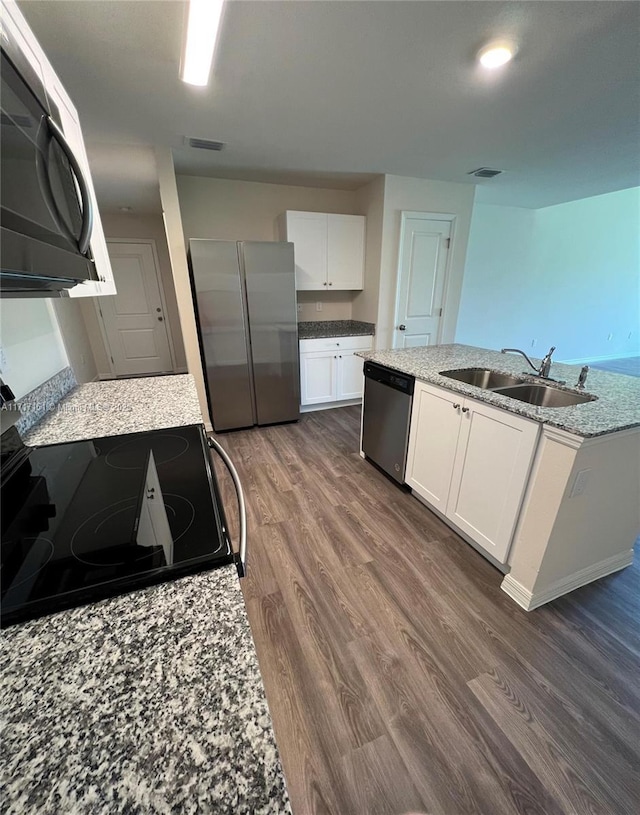 kitchen with dark wood-type flooring, white cabinets, sink, light stone countertops, and stainless steel appliances