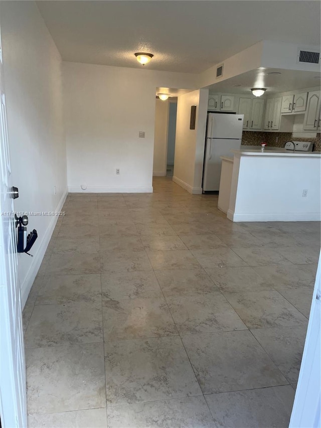 kitchen with white refrigerator and tasteful backsplash