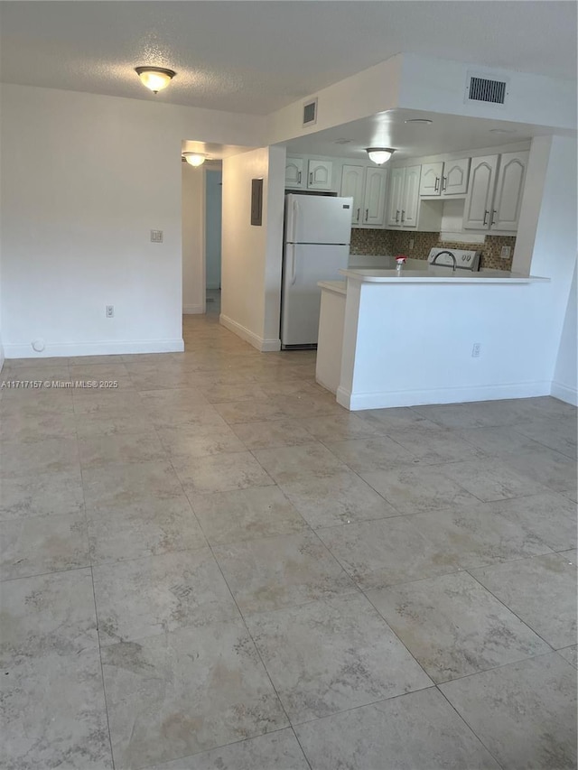 kitchen featuring backsplash, kitchen peninsula, and white fridge