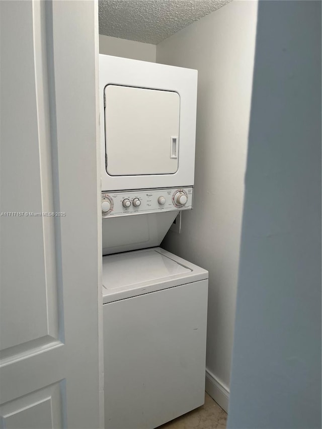 laundry room featuring a textured ceiling and stacked washer / dryer