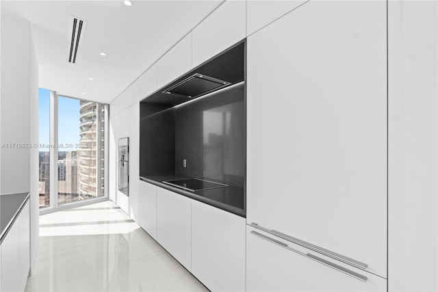 kitchen featuring white cabinetry, expansive windows, and black electric stovetop