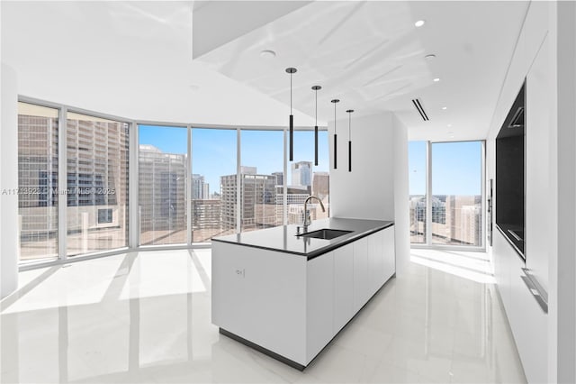 kitchen featuring sink, white cabinetry, expansive windows, light tile patterned flooring, and decorative light fixtures