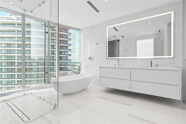 bathroom with independent shower and bath, vanity, tile walls, and tile patterned floors