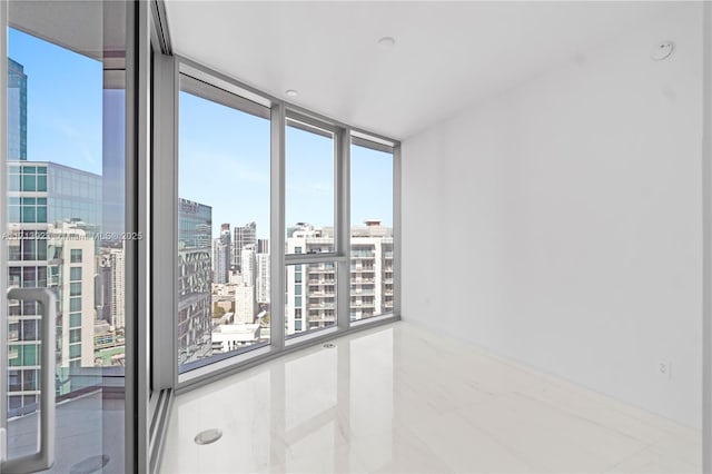 empty room featuring light tile patterned flooring and a wall of windows