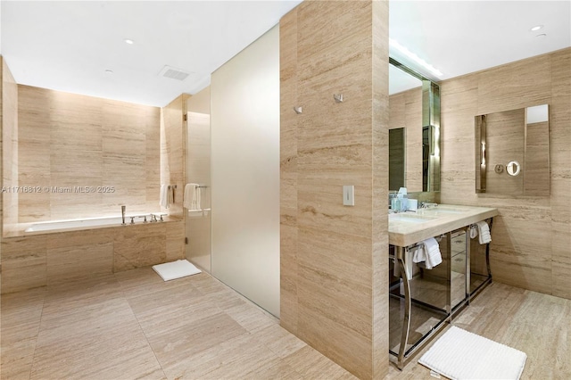 bathroom featuring tile patterned floors, tiled tub, and tile walls