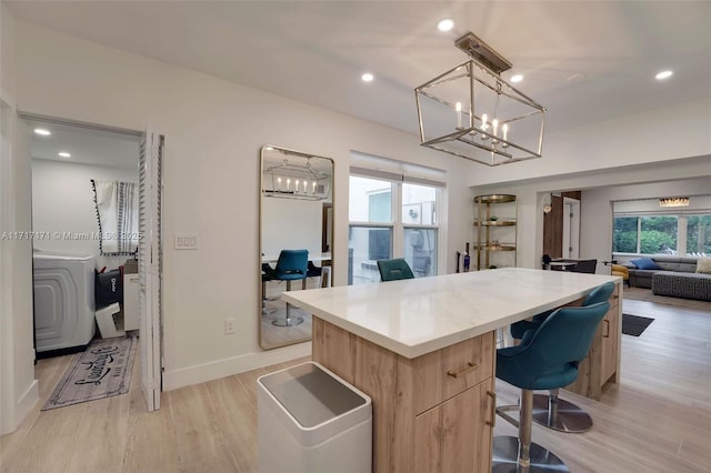 kitchen featuring pendant lighting, a center island, light hardwood / wood-style floors, light brown cabinetry, and washer / clothes dryer