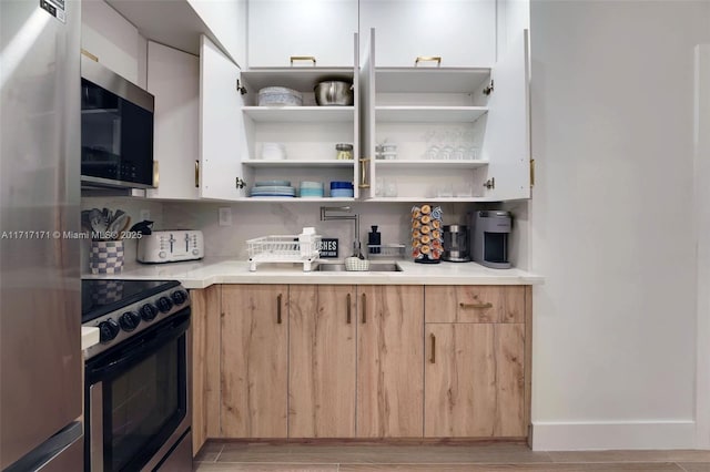 kitchen featuring backsplash, light wood-type flooring, white cabinets, and appliances with stainless steel finishes