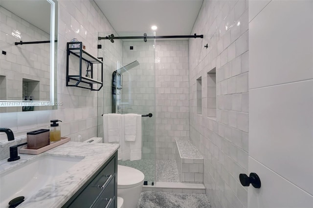 bathroom with tile walls, an enclosed shower, vanity, and toilet